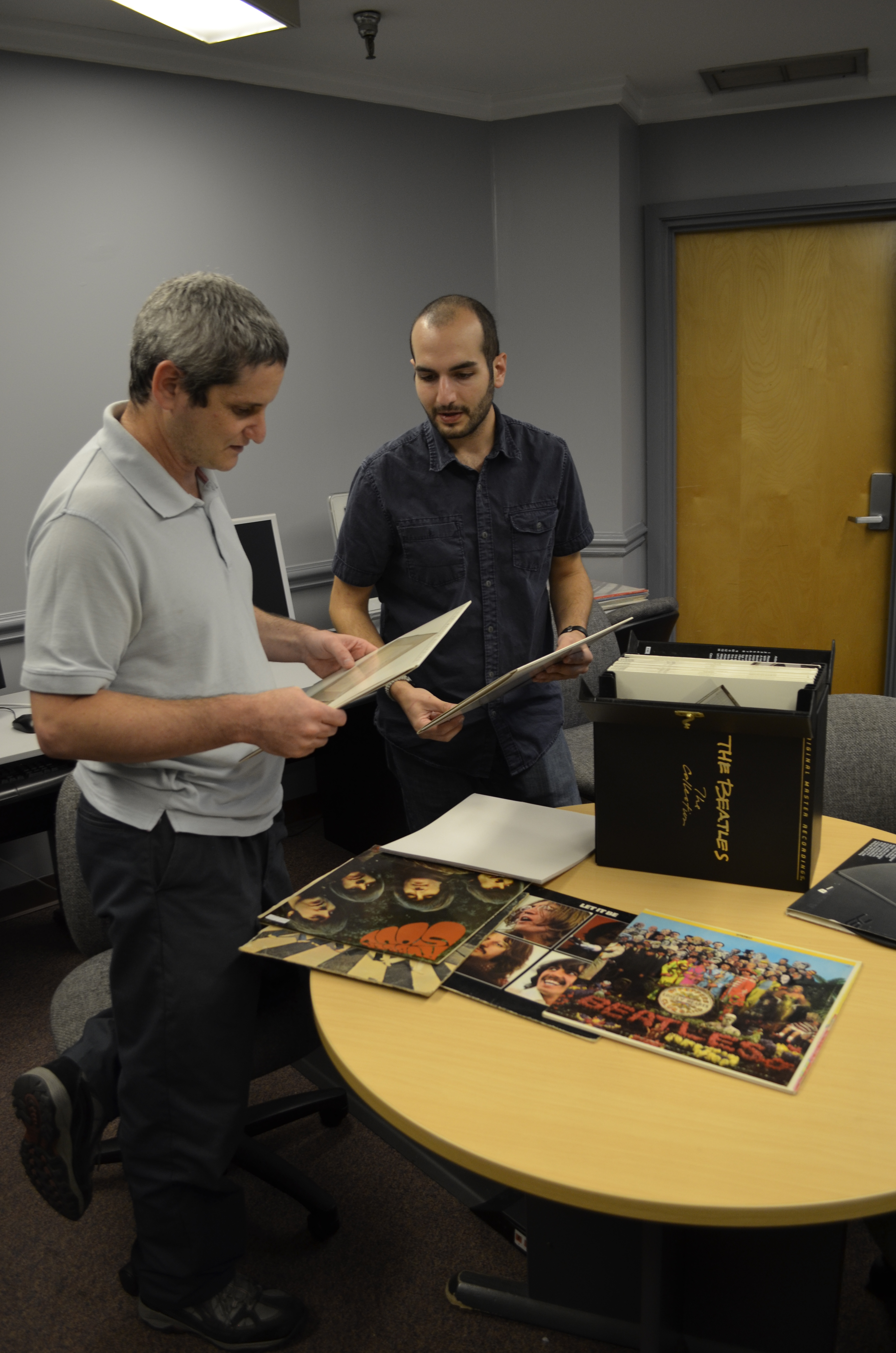 Lawrence Tech Associate Professor Lior Shamir (left) and graduate student Joe George look over the liner notes on some of the Beatles albums that they analyzed in a recent research study.